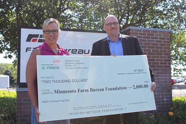 Minnesota Farm Bureau Foundation Director Ruth Meirick accepts a donation from Joe Martin of DuPont Pioneer.